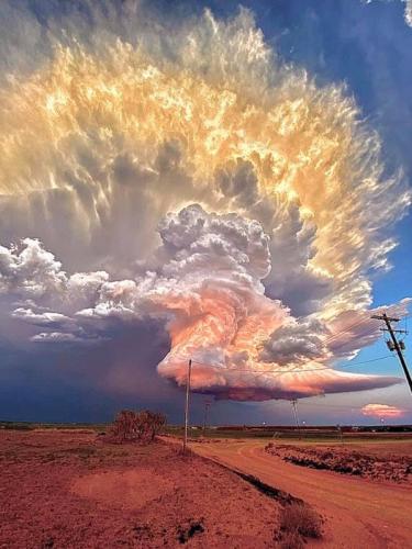 Mature supercell thunderstorm, illuminated at varying heights from the setting sun