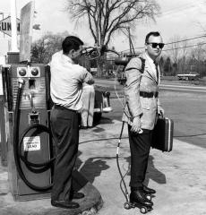 1961 Salesman having motorized roller skates refueled with gasoline